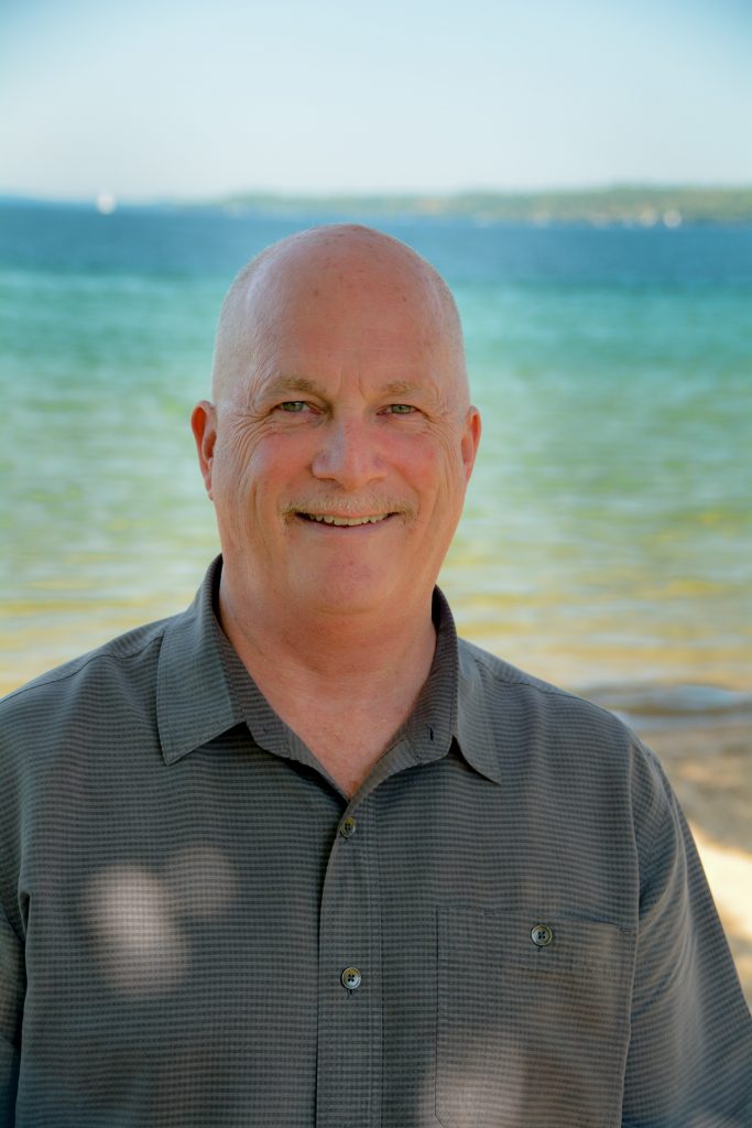 Steve Barnes smiling infront of the beach